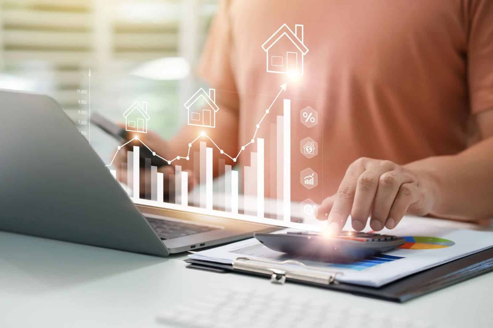 Person using a calculator and laptop to review rental property financial data with charts and real estate investment growth graphics.
